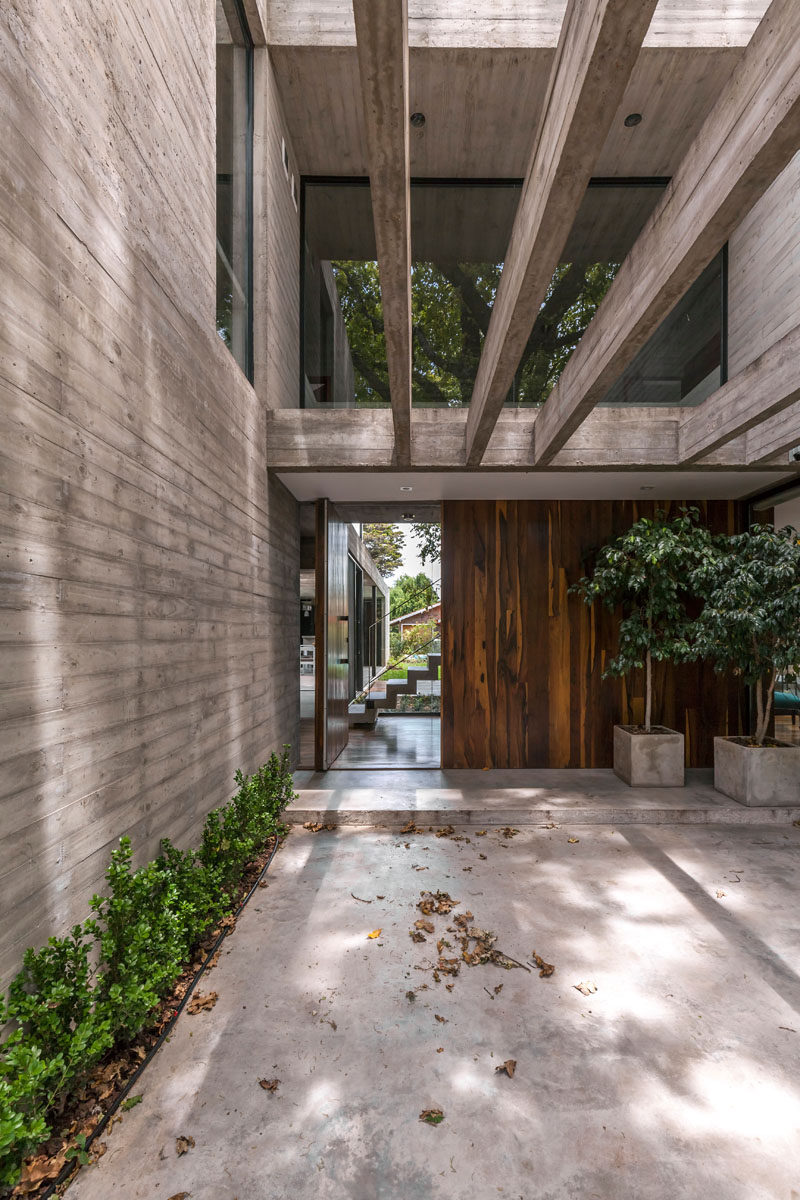 A large pivoting wood front door welcomes you to this modern house, and when open, it gives you a glimpse of the backyard.