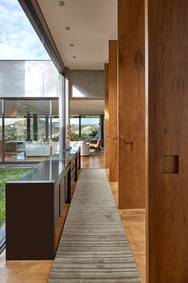 Stepping inside this modern house, large windows surround an internal garden, while a hallway leads to the main living areas of the home. #Windows #Hallway