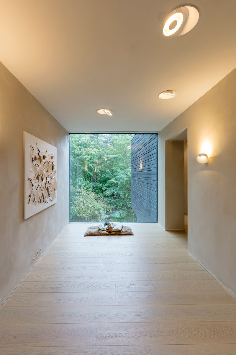 A large picture window at the end of this hallway provides the perfect place to sit on come cushions and watch nature. #Windows #Hallway