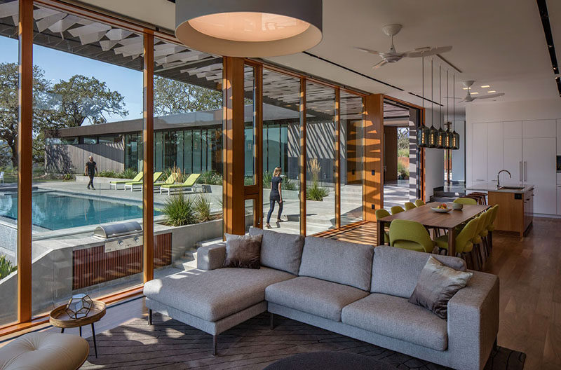 Wood framed floor-to-ceiling windows give this living area a view of the pool outside.