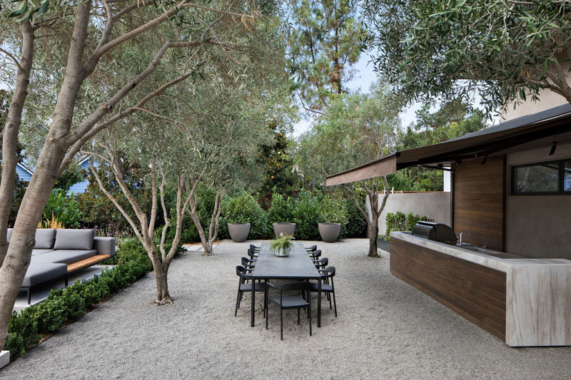 This outdoor kitchen and dining area looks out to the pool, and sits among a grove of olive trees. #OutdoorKitchen #AlfrescoDining #Landscaping