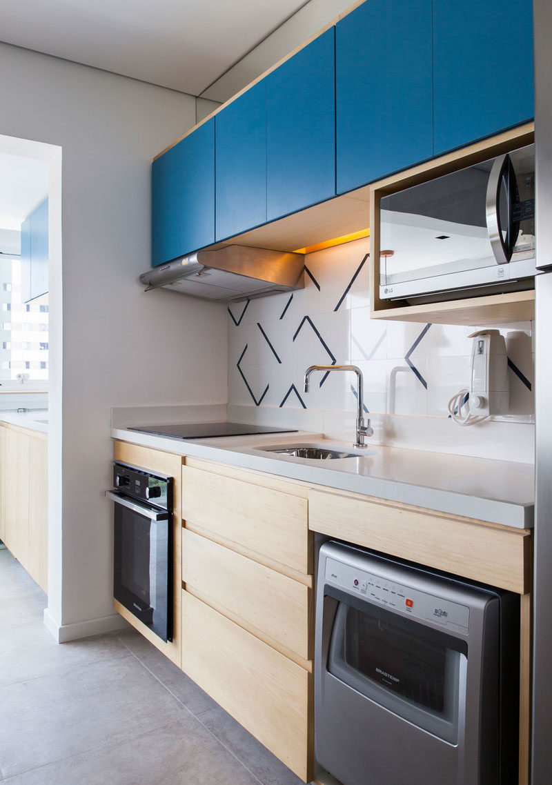 In this small and modern kitchen, bright blue cabinet fronts add a pop of color to the wood cabinetry. #SmallKitchen #KitchenDesign