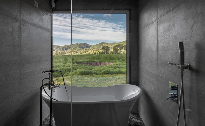 In this modern bathroom, a freestanding bathtub sits in front of another large window that perfectly frames the surrounding landscape. #ModernBathroom #Window