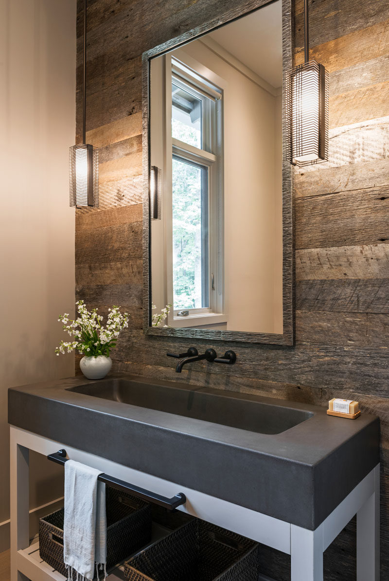 In this rustic modern bathroom, a wood accent wall has been included in the design and an all-in-one concrete vanity and sink sit on a white frame. #Bathroom #RusticModern