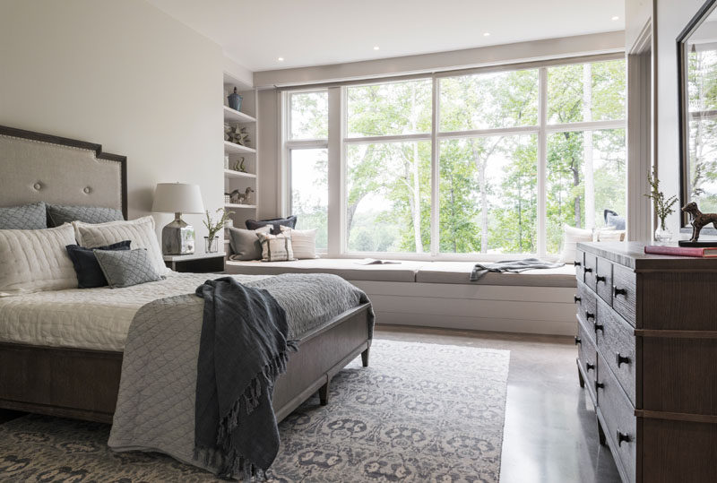 In another bedroom, there's a built-in window seat that runs the length of the windows, and at one end, there's a built-in bookshelf. #Bedroom #WindowSeat #Shelving