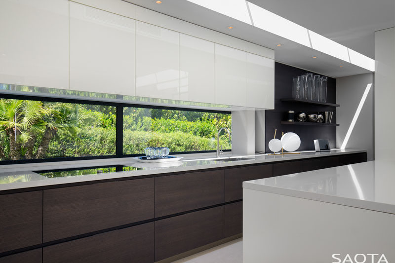 In this kitchen, hardware-free white upper cabinets have been paired with wood lower cabinets and open shelving for a minimalist look. #MinimalistKitchen #KitchenDesign