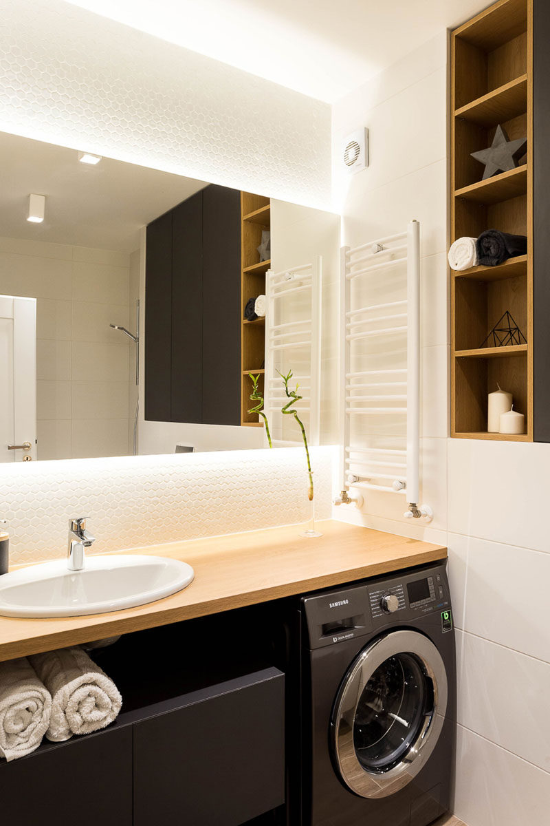 This modern bathroom has a cabinet on the wall creates plenty of storage, while wood lined open shelving is the perfect place to display some simple decor. A backlit mirror provides ambient lighting to the space. #ModernBathroom #BacklitMirror