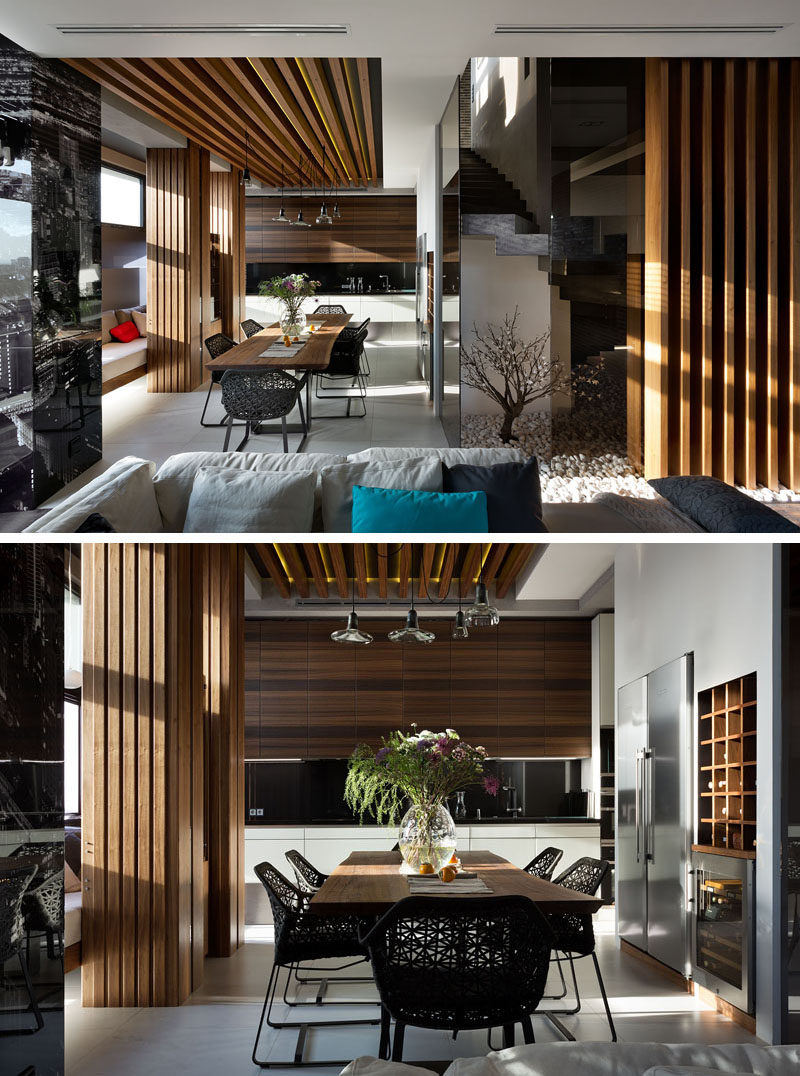 This modern dining room has a wood dining table and ceiling feature. A built-in bench sits against the wall and at the end of the dining room is the kitchen. #ModernDiningRoom #InteriorDesign