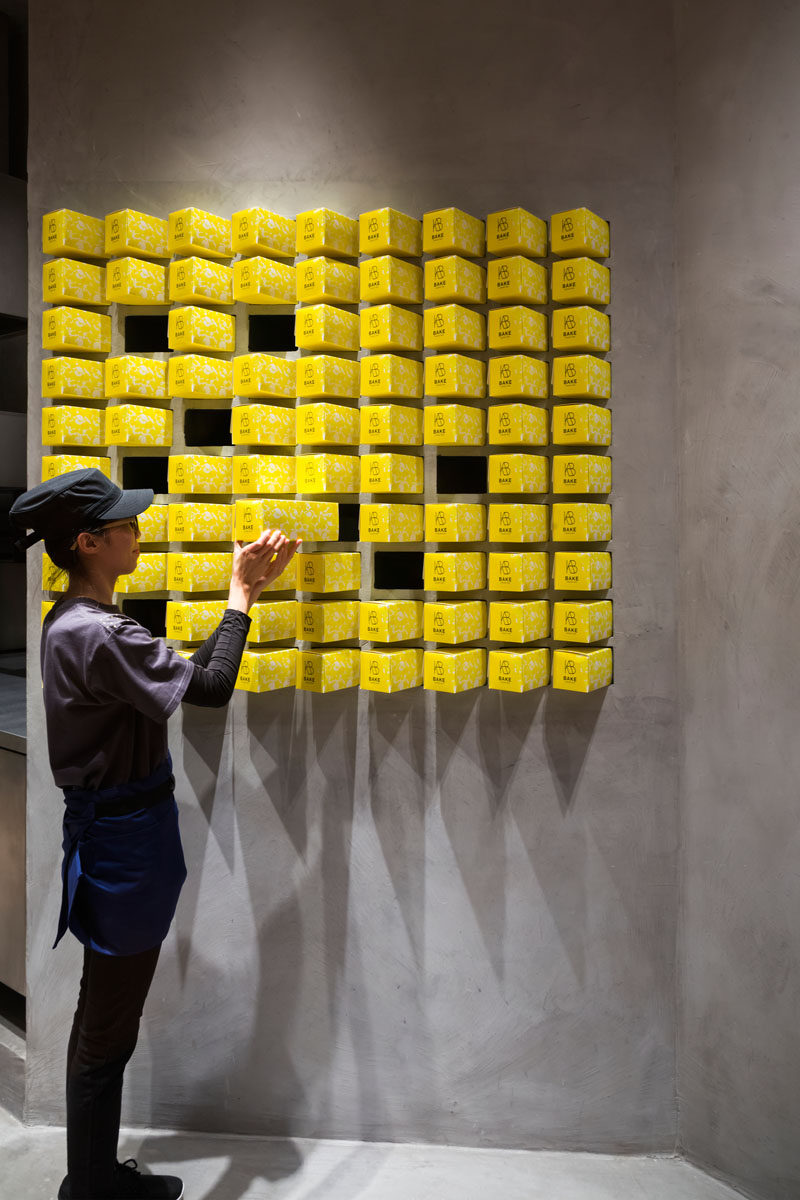 In this modern bakery, pops of yellow have been included in the design with the use of packaging. Custom nooks were created so that they can perfectly house the packaging. #ModernBakery #RetailDesign #Packaging