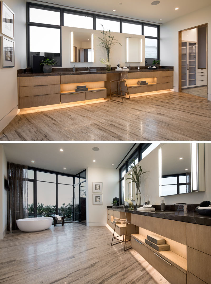 In this modern master bathroom, a large vanity with dual sinks lines the wall and a freestanding bathtub sits in front of the windows. Off to the side of the bathroom is a large walk-in closet. #MasterBathroom #BathroomDesign