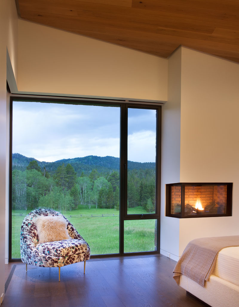 This modern bedroom has a built-in fireplace and a large window to let in plenty of natural light. #Fireplace #Windows