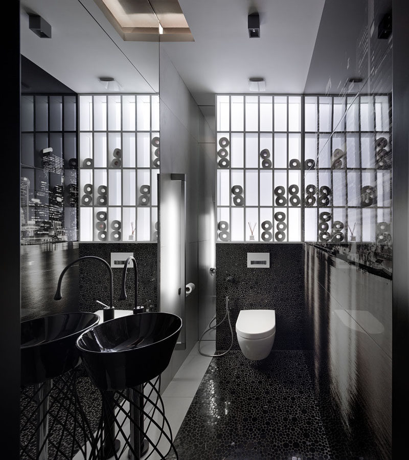 In this bathroom, black tiles and a black sink contrast the white shelving to create a modern appearance. #BlackAndWhite #ModernBathroom