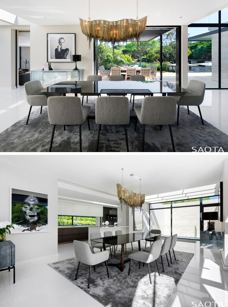 In this modern dining room, a bespoke chandelier hangs over the dining table and adds a touch of luxury to the space, while light vein cut travertine floors contrast the black slim line sliding doors. #DiningRoom #Flooring