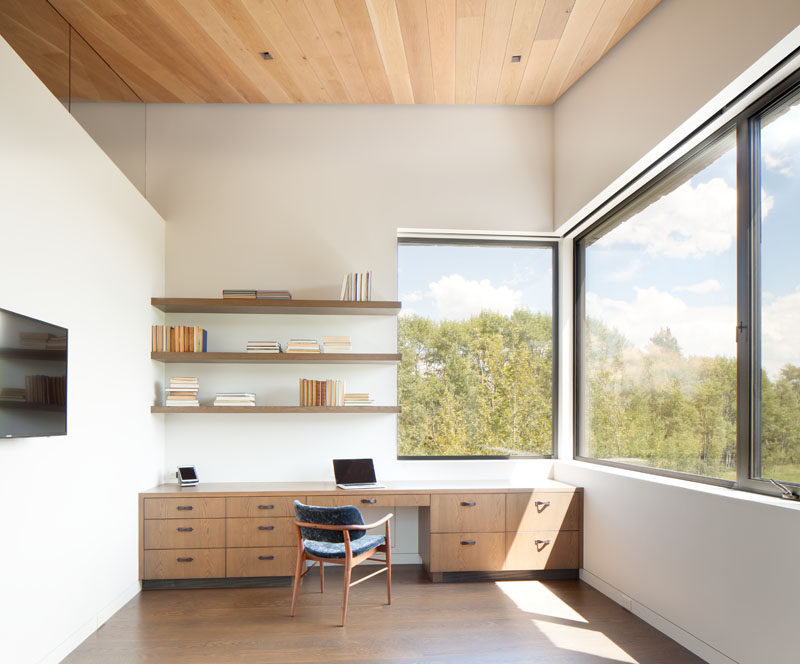 This modern home office has a long desk that has plenty of storage, and simple wood shelving installed above it. #HomeOffice