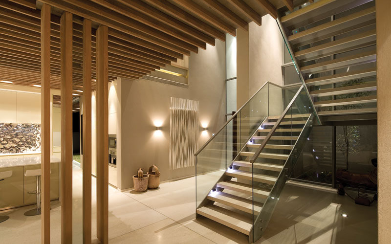 Inside this modern house, there's a double-volume entry hallway and aligned timber slat clad ceilings drawing the eye to the seascape ahead. #Entryway #Stairs