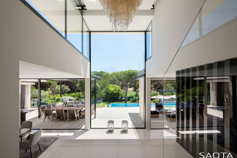 Stepping inside this modern house, there's a capiz shell chandelier occupies the double volume entrance hall area and large frameless windows allow for views over the pool and garden area. #InteriorDesign #Windows