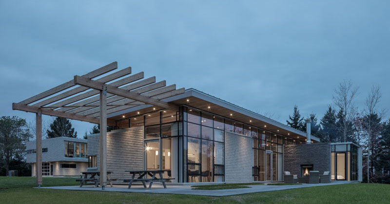 This modern house in Nova Scotia has an extended roof that creates a pergola for an outdoor entertaining space. #ModernHouse #ModernPergola