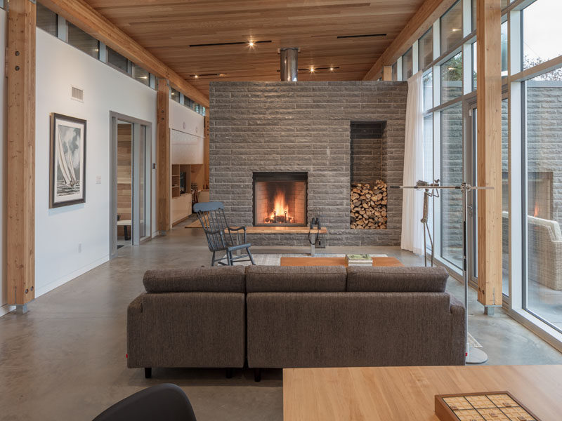 In the living room of this modern house, a stone fireplace surround has been built to accommodate firewood storage. #Fireplace #WoodStorage