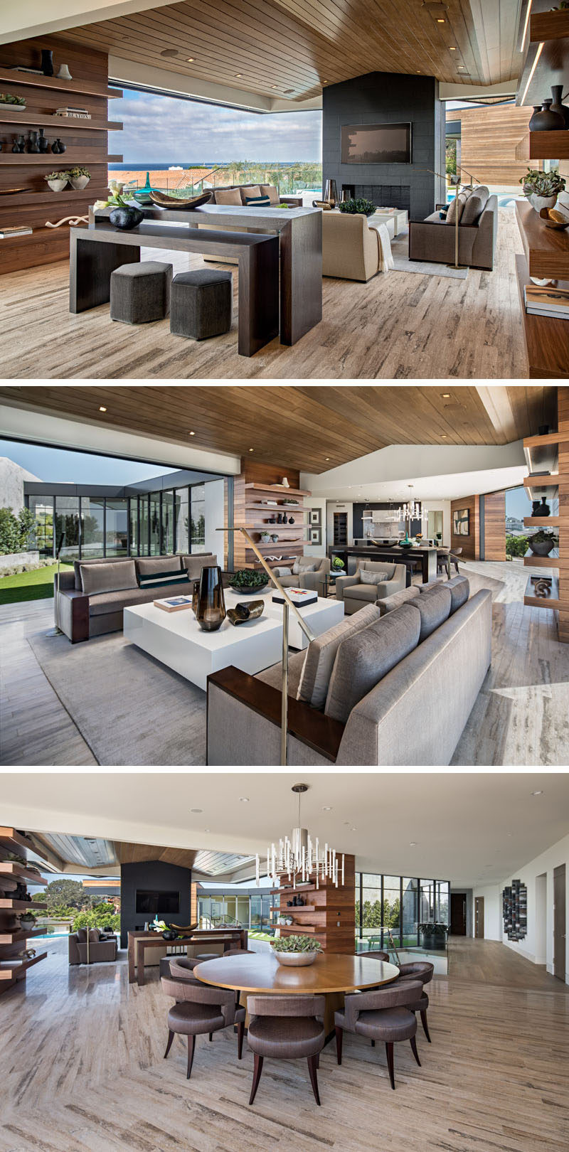 The main living area of this modern house is almost completely open to the outdoors. The living room, with a wood ceiling, is focused on the fireplace and the view, while the circular dining table separates the living room from the kitchen. #ModernLivingRoom #DiningRoom #InteriorDesign