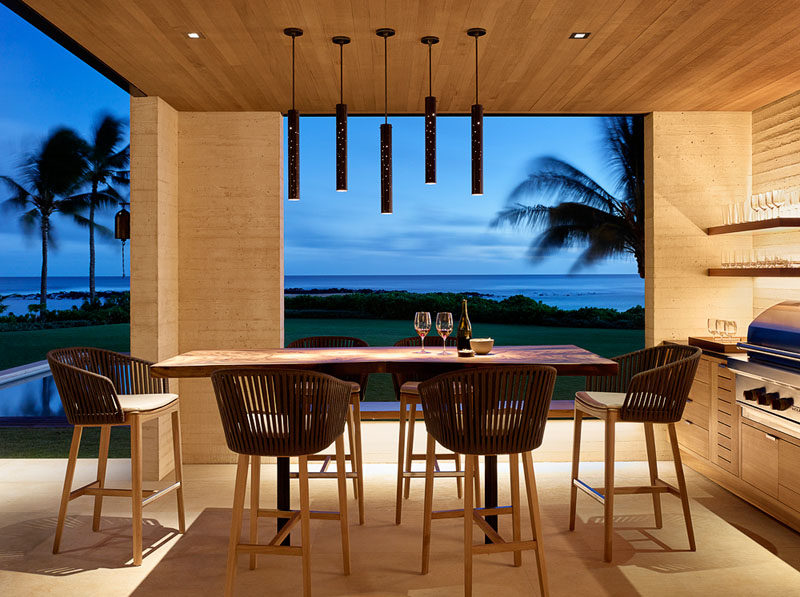 This modern beach house has a covered outdoor kitchen with a barbecue and an alfresco dining area.