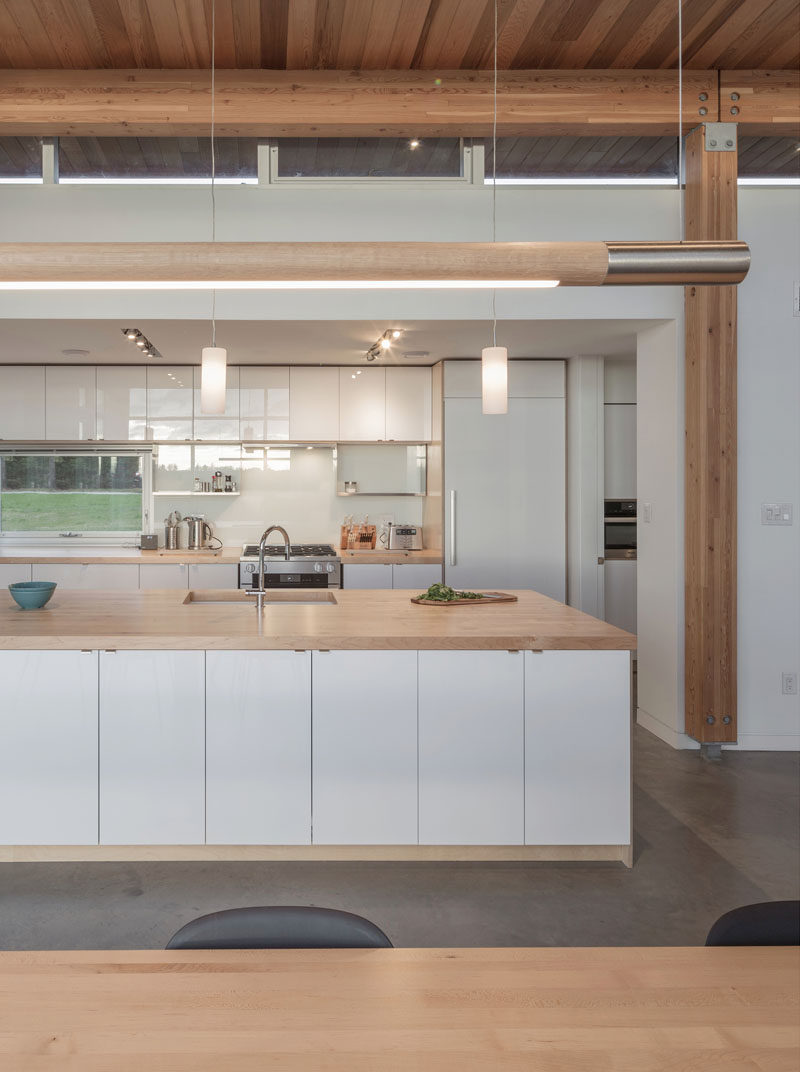 In this modern kitchen, minimalist white cabinets have been paired with wood counters to create a contemporary appearance. #ModernKitchen #WhiteAndWoodKitchen