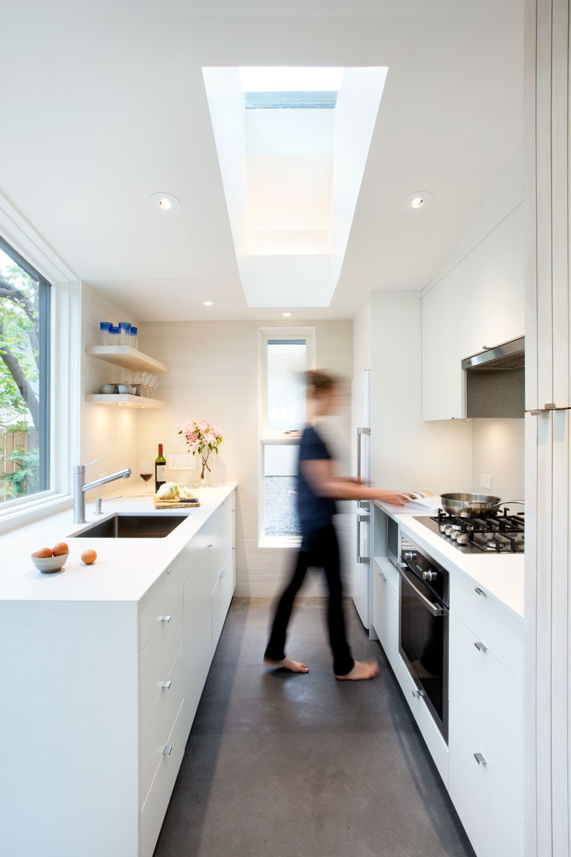 This small kitchen has white cabinets and plenty of windows to allow natural light to brighten the space and make it feel larger. #SmallKitchen #WhiteKitchen #Skylight