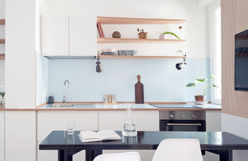 this small apartment kitchen has a light blue backsplash and white cabinets to keep it bright. #KitchenDesign #SmallKitchen