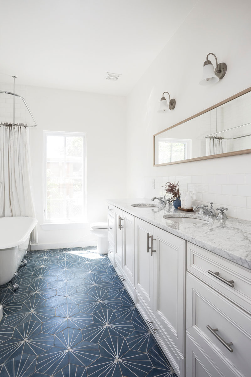 A blue dandelion tile adds a pop of color to this contemporary white bathroom. #BlueTile #BathroomDesign