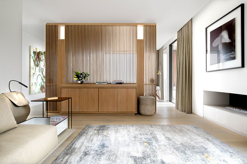 In this modern sitting area, there's a built-in fireplace and a wood slat wall that separates the room. #LivingRoom #Fireplace