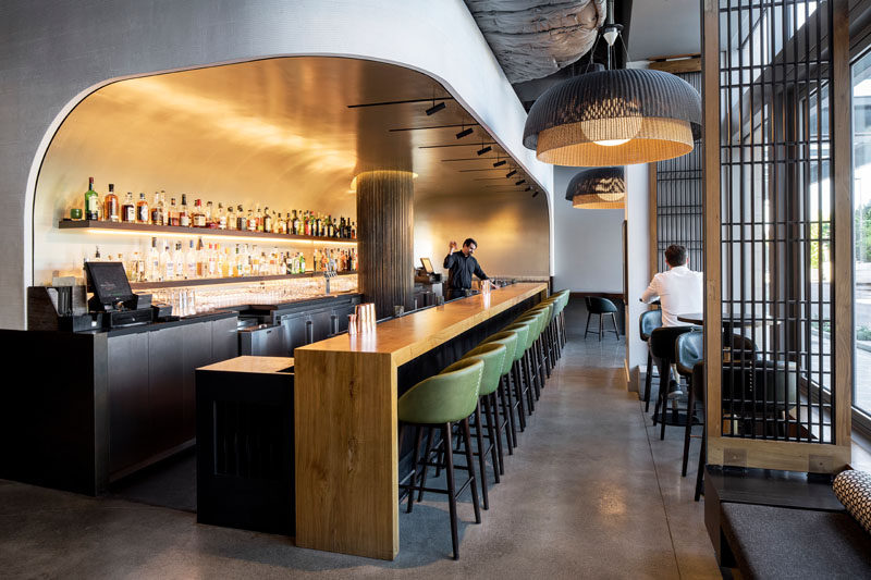 The bar in this modern restaurant appears to be set into a curved niche, that's been finished with silver leaf squares, creating a luxurious, subtly reflective backdrop. #ModernBar #RestaurantDesign