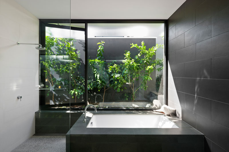 In this modern bathroom, there's a built-in bathtub that sits beside the shower. A window that opens to the garden makes it feel like you're showering outside. #ModernBathroom #BuiltInBathtub #Windows