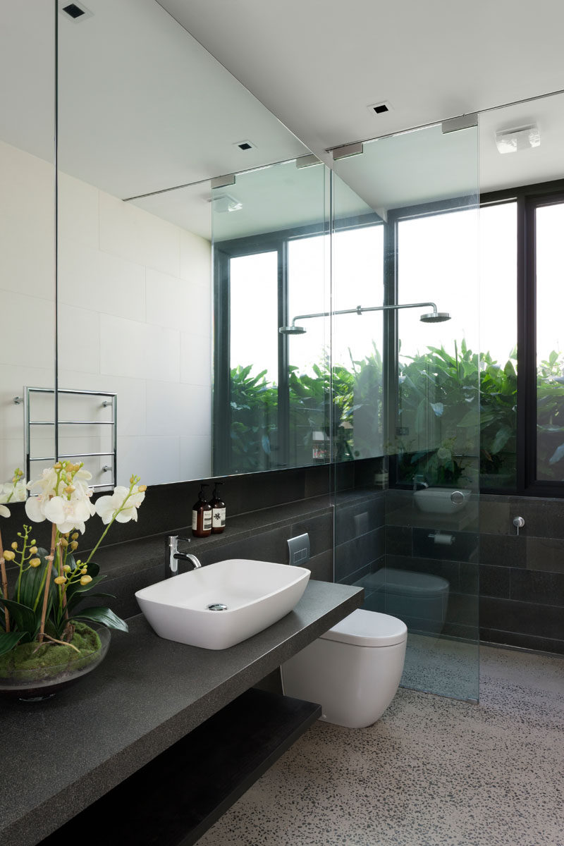 In this modern bathroom, a large window travels through from the vanity area to the shower, helping to reflect light throughout the space. #ModernBathroom #BathroomMirror