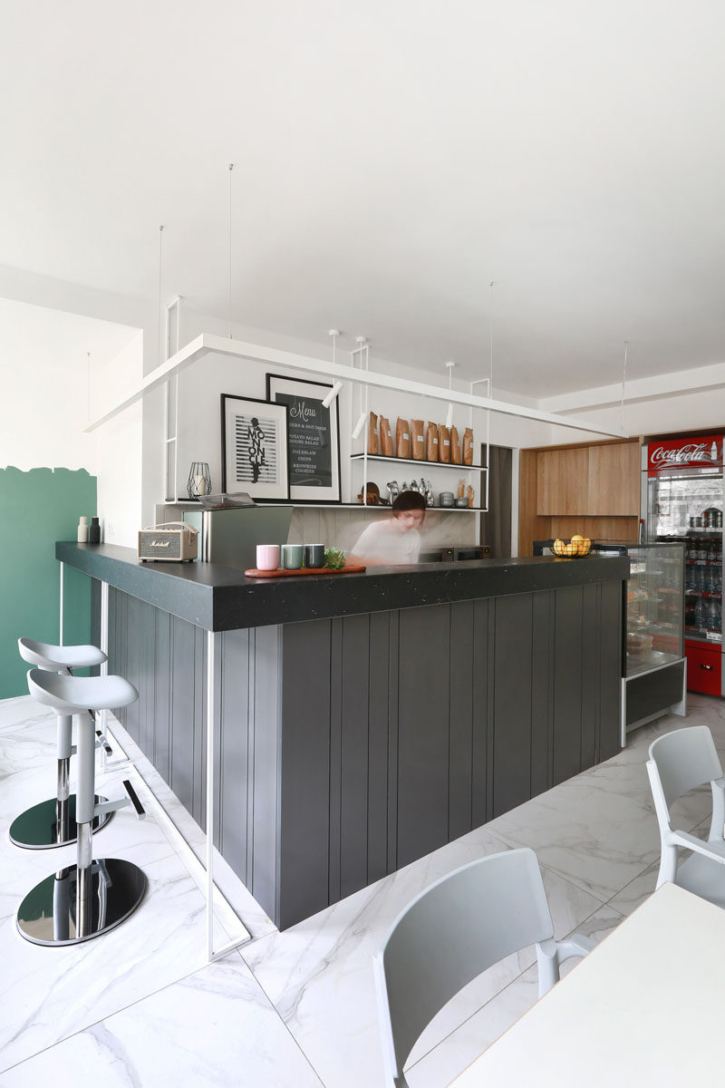 This modern coffee shop has a dark grey service counter with a darker countertop has been designed to have space for bar stools. #CoffeeShop #CafeDesign