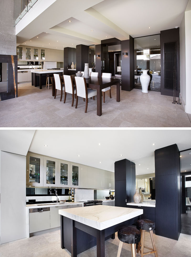 This contemporary dining room has a dark wood dining table, while in the kitchen, light colored cabinets contrast the darker cabinets and help to keep the space bright. #DiningRoom #Kitchen