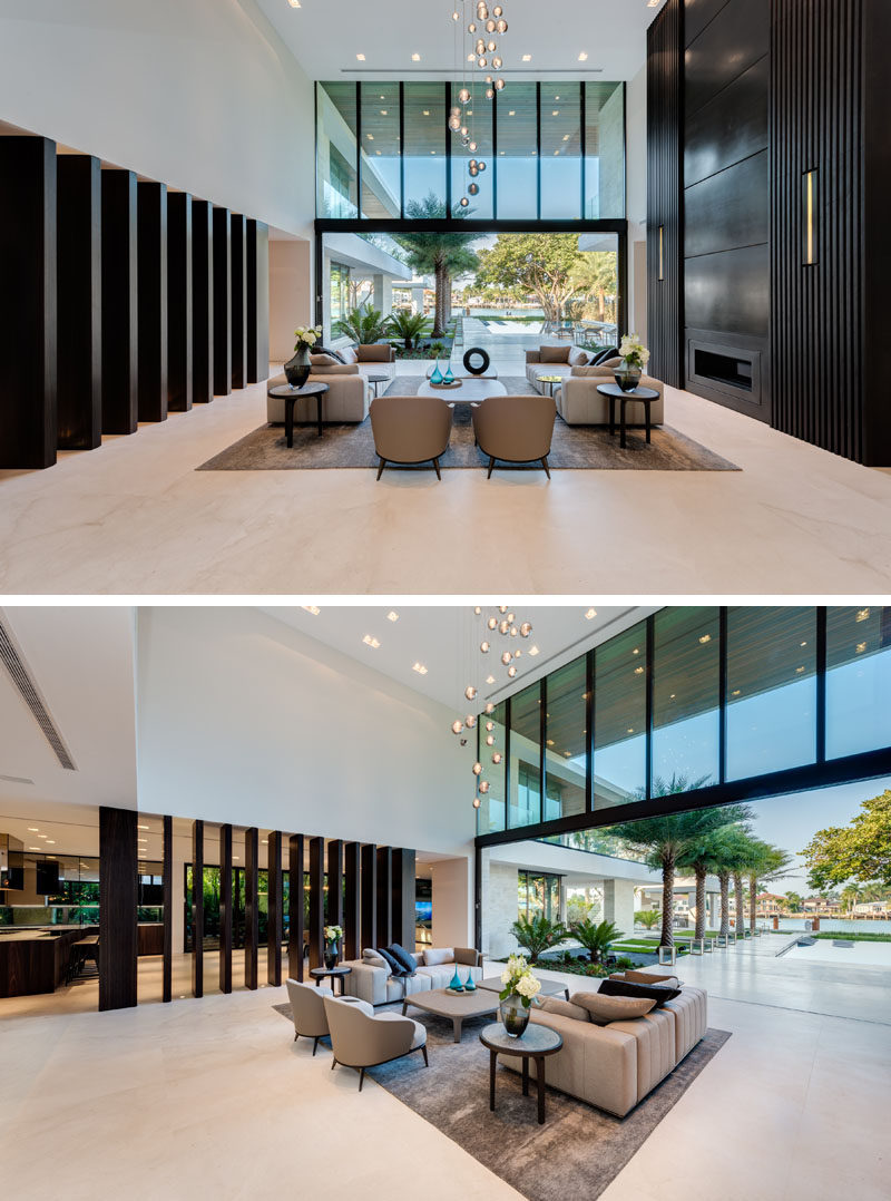 A living room with a two-story bronze fireplace on one wall and a large glass wall that opens to the backyard.