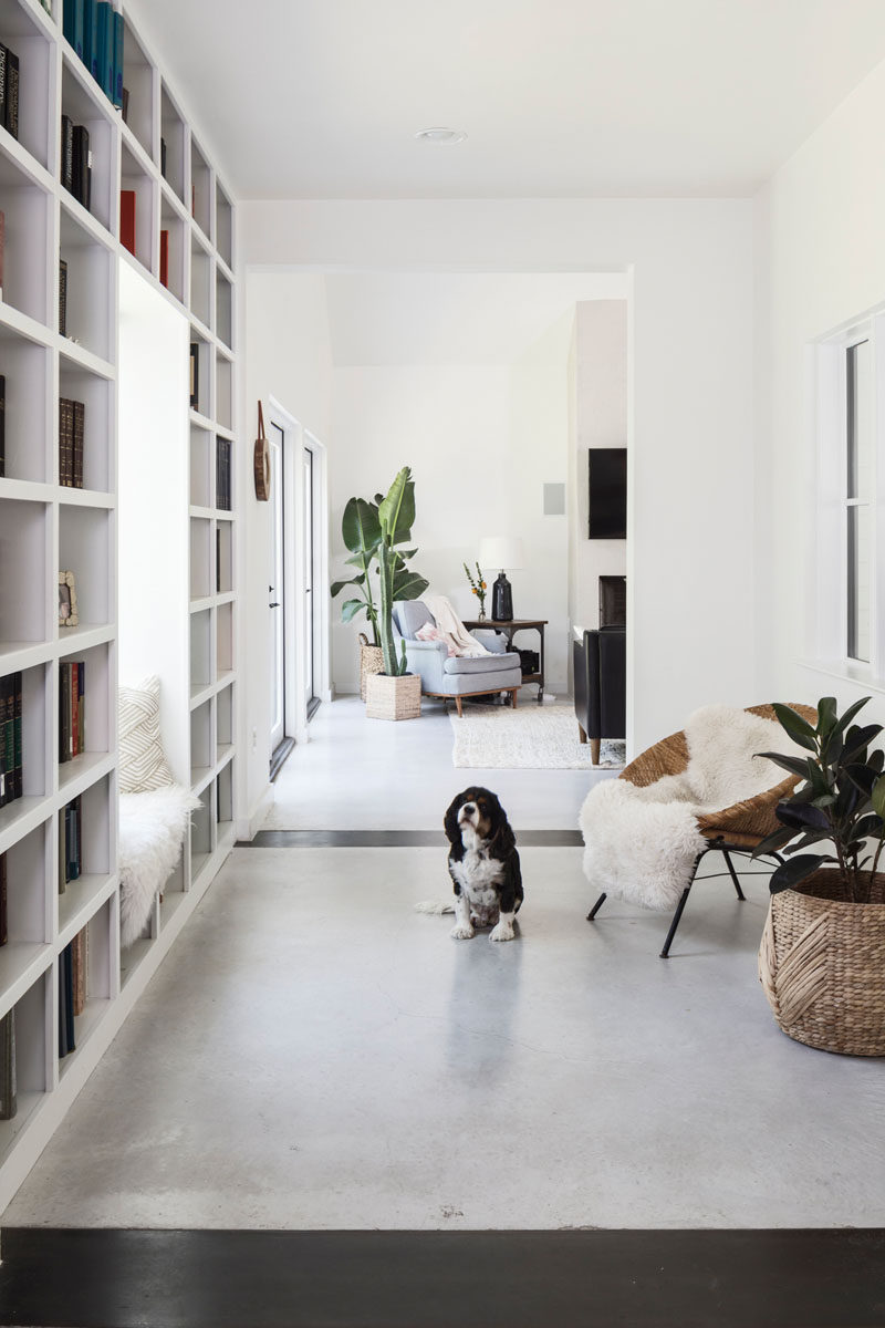Stepping inside this contemporary house, the entryway has a window seat surrounded by bookshelves, and it opens up into the main social areas of the house. #Bookshelf #Entryway #InteriorDesign