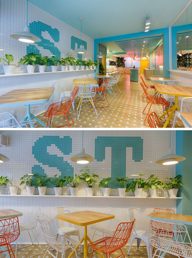 At the front of this modern ice cream store, there's a tiled wall with plants on one side, and on the opposite wall, there's mirrors that help to make the space feel larger. #IceCreamStore #RetailDesign