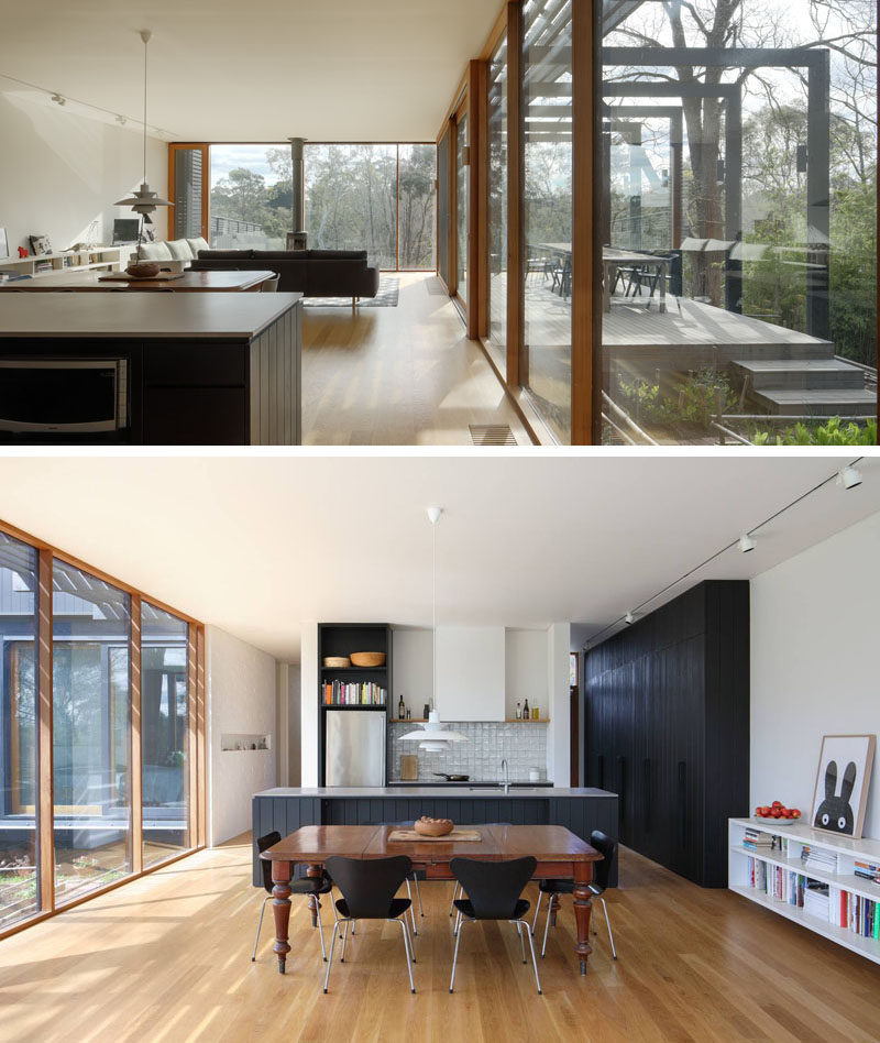 Inside this modern house extension, there's a new living room, dining area and kitchen, that all feature white walls, American oak floors with an oil finish and cedar windows. Black cabinets in the kitchen tie in with the black exterior of the extension. #BlackKitchen #OpenFloorPlan #HouseExtension