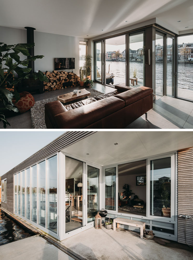 In the living room of this modern houseboat, there's a wood-burning fireplace for colder months, and in the warmer months, a sliding door can be opened to provide access to a small deck. #Fireplace #Windows #LivingRoom