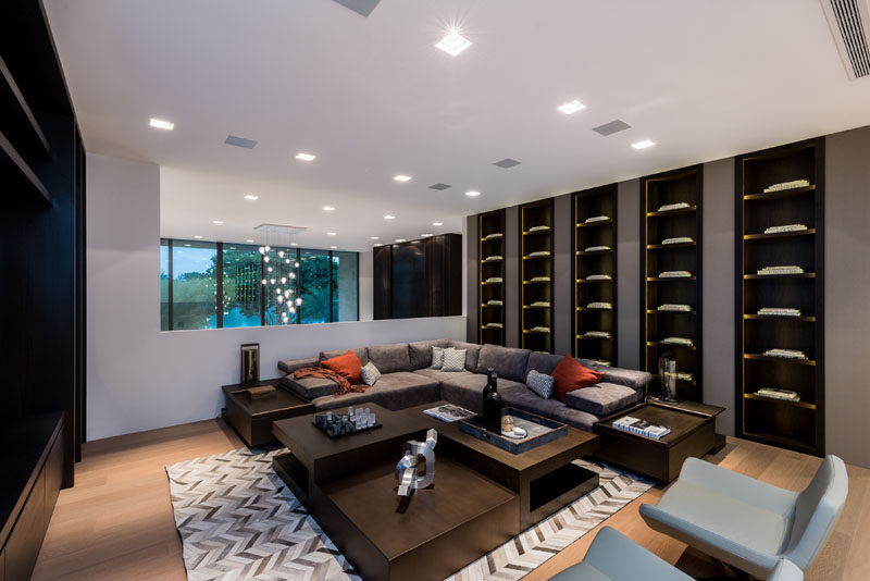 A modern living room with an L-shaped couch and a wall of dark wood built-in shelving.