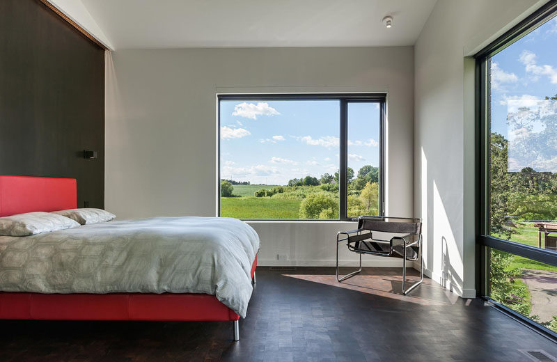 In this master bedroom, large windows provide views of the trees and the surrounding landscape. #MasterBedroom #Windows