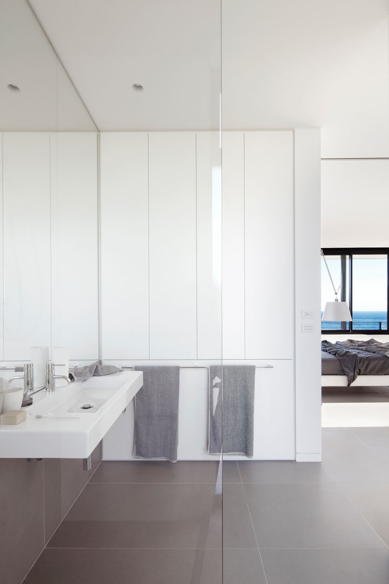 A large mirror and white walls in this master bathroom makes the space feel large, while the tiles from the floor travel onto the wall to meet the vanity. #MasterBathroom