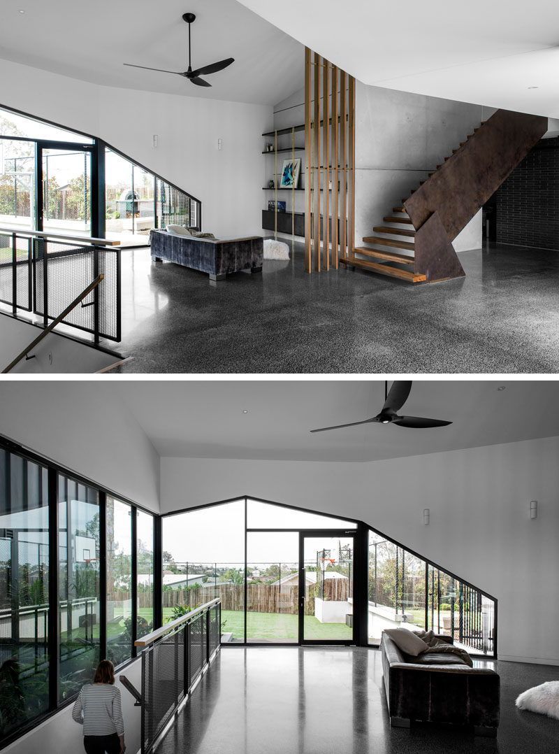 This modern house has an open entryway with a sitting / reading area with shelving against the wall. #SittingArea #Entryway #Windows