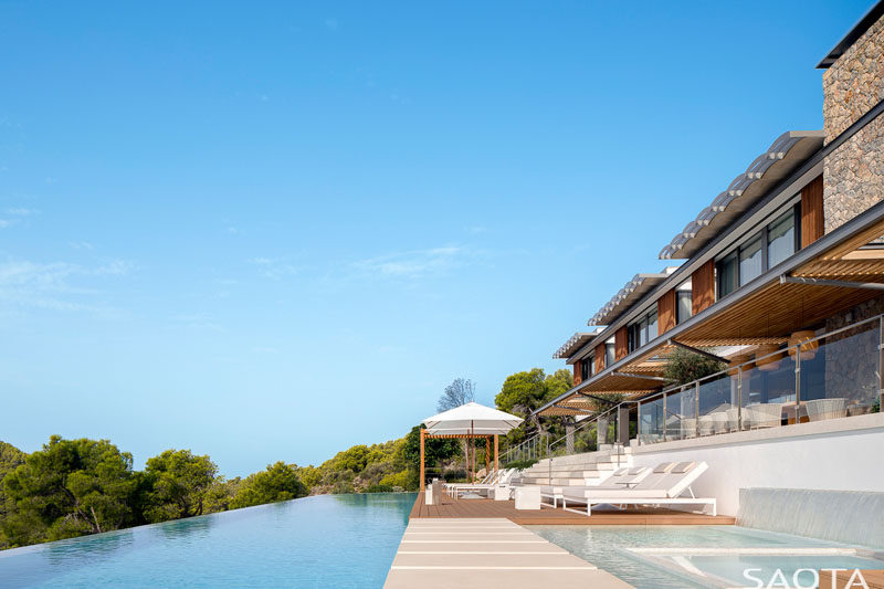 The swimming pool of this modern house looks out over the surrounding landscape and a deck with sun chairs provides a place to relax in the sun. #SwimmingPool #ModernHouse