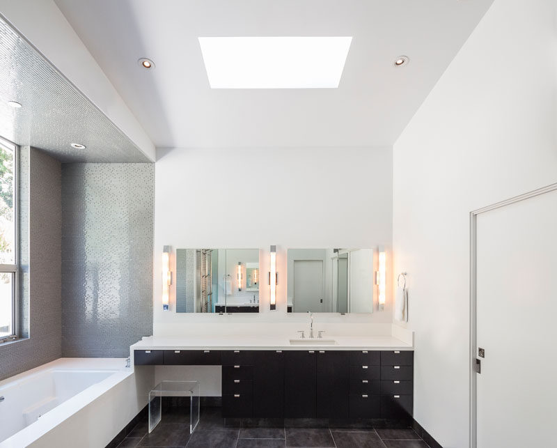 In this modern and minimal bathroom, a black vanity is topped with a white countertop that matches the walls, ceiling and bath. #Bathroom #ModernBathroom