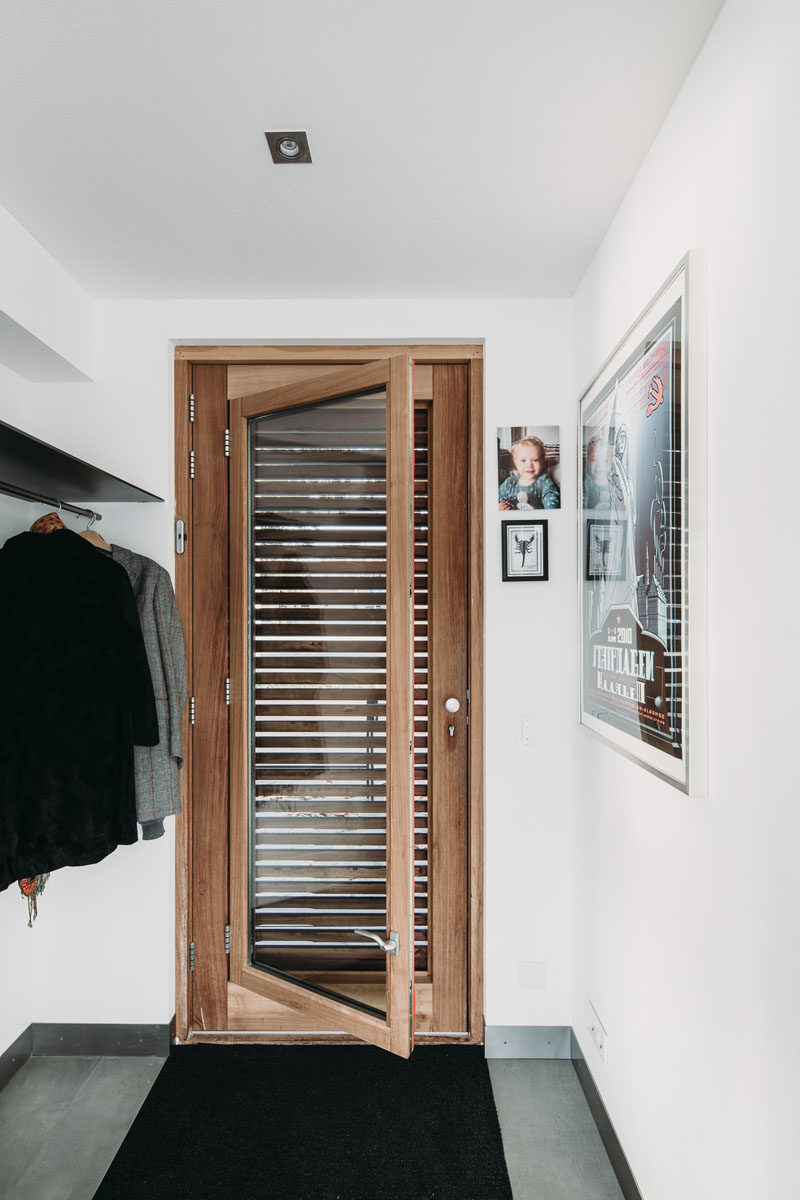 Hidden behind the exterior door on this modern floating villa is an interior door with a built-in window. In the entryway, there's a built-in space for hanging coats and placing shoes. #Door #FrontDoor #DoorWithWindow #Entryway