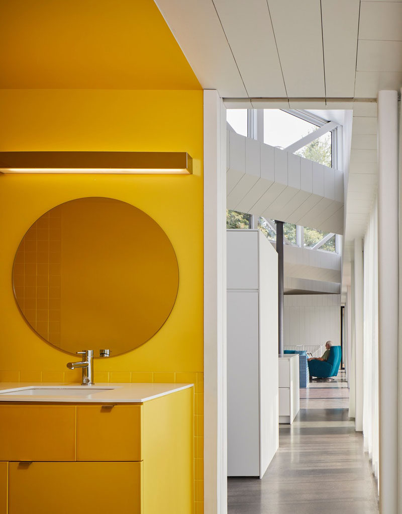 This modern house has a bright yellow bathroom that stands from the mostly white interior. #YellowBathroom #ModernBathroom