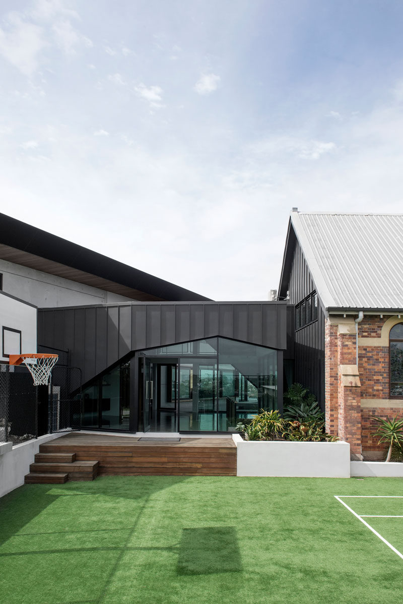 This modern house that connects with a renovated church has an an outdoor space with a tennis court and basketball hoop #ModernLandscaping #Architecture