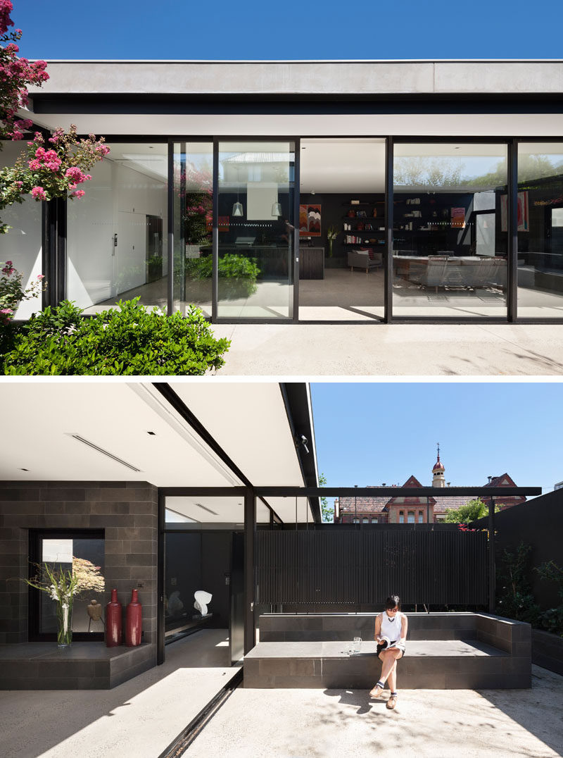 Sliding glass doors open the interior spaces of this modern house to a private courtyard filled with plants and seating. #GlassWall #ModernHouse #Courtyard