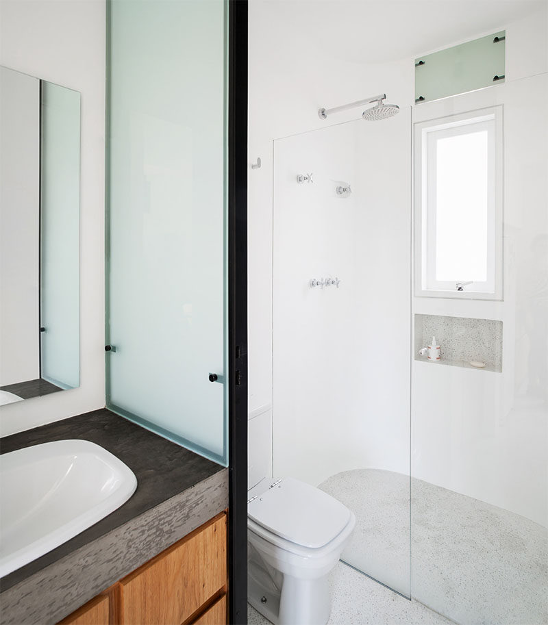 This small bathroom has a wood and concrete vanity and a walk-in shower. #SmallBathroom #BathroomDesign